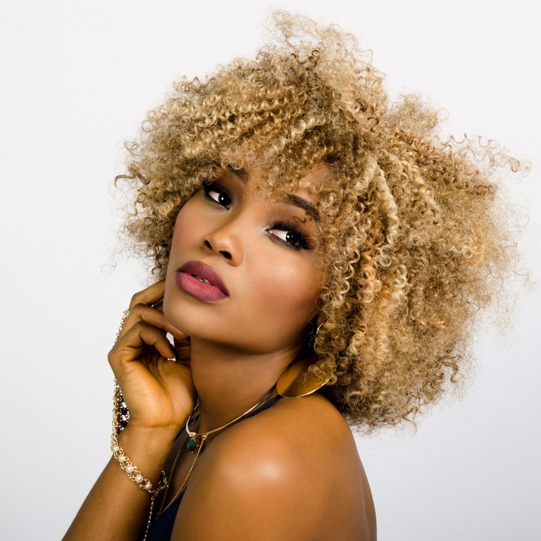 Brunette woman with curly blond hair and pinched bangs 